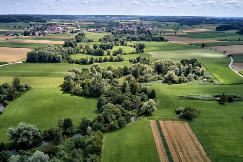 Blick aus der Luft auf schöne Landschaft mit Wiesen, Bäumen und Feldern.