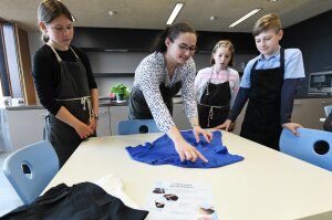 Lehrerin zeigt Gruppe von Schülern wie man T-Shirts faltet