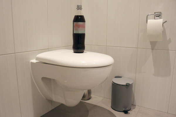 Eine Flasche Cola auf einer Toilettenschüssel.