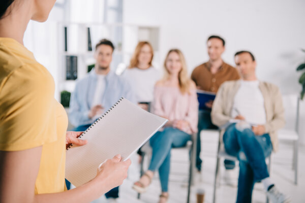 Person referiert vor einer Gruppe Seminarteilnehmender.