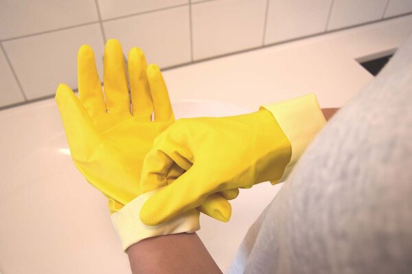 Behandschuhte Hand vor einem Waschbecken