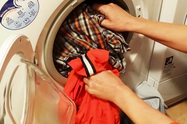 Person füllt eine Waschmaschine