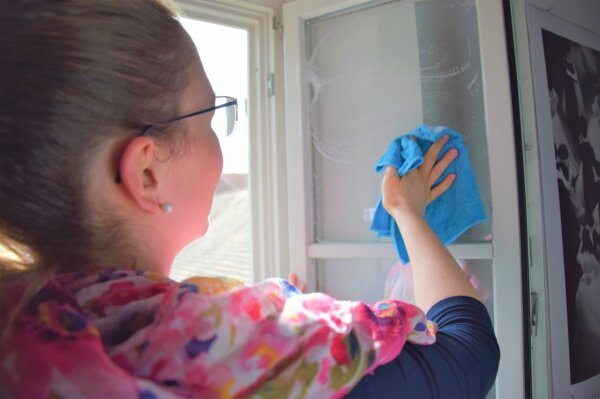 Frau reinigt Fenster.