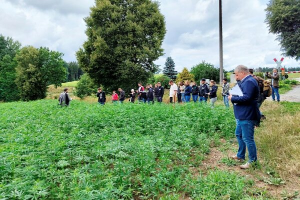 Landwirt Gerhard Adam steht am Feldrand und erklärt in seinem Nutzhanffeld den interessierten Studierenden die Bewirtschaftung von Hanf .