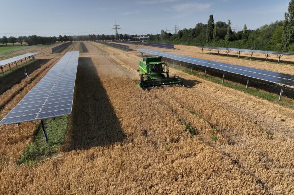 Photovoltaik-Module auf einem Acker, über den ein Traktor fährt