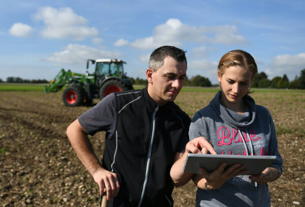 Landwirtschaftliches Unternehmerpaar mit Laptop auf dem Feld