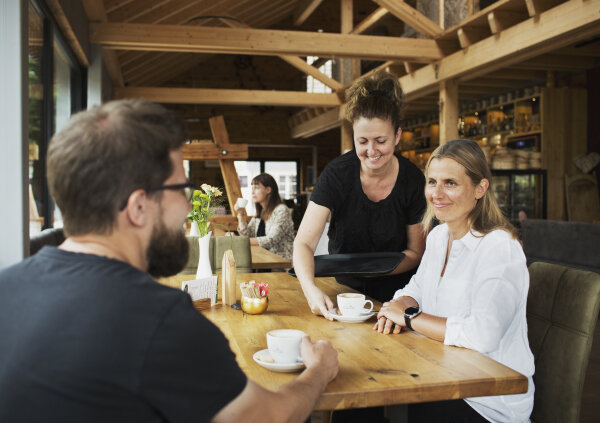 Personen sitzen an einem Holztisch in einem Café