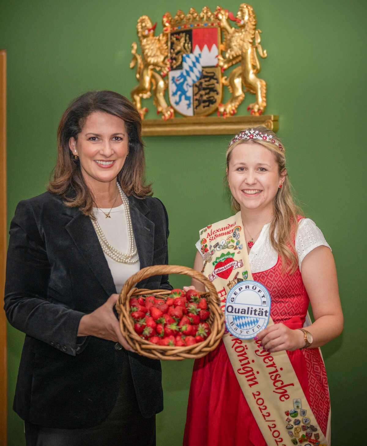 Ministerin Kaniber hält einen Korb mit Erdbeeren. Neben ihr steht die 1. Bayerische Erdbeerkönigin Alexandra Stömmer