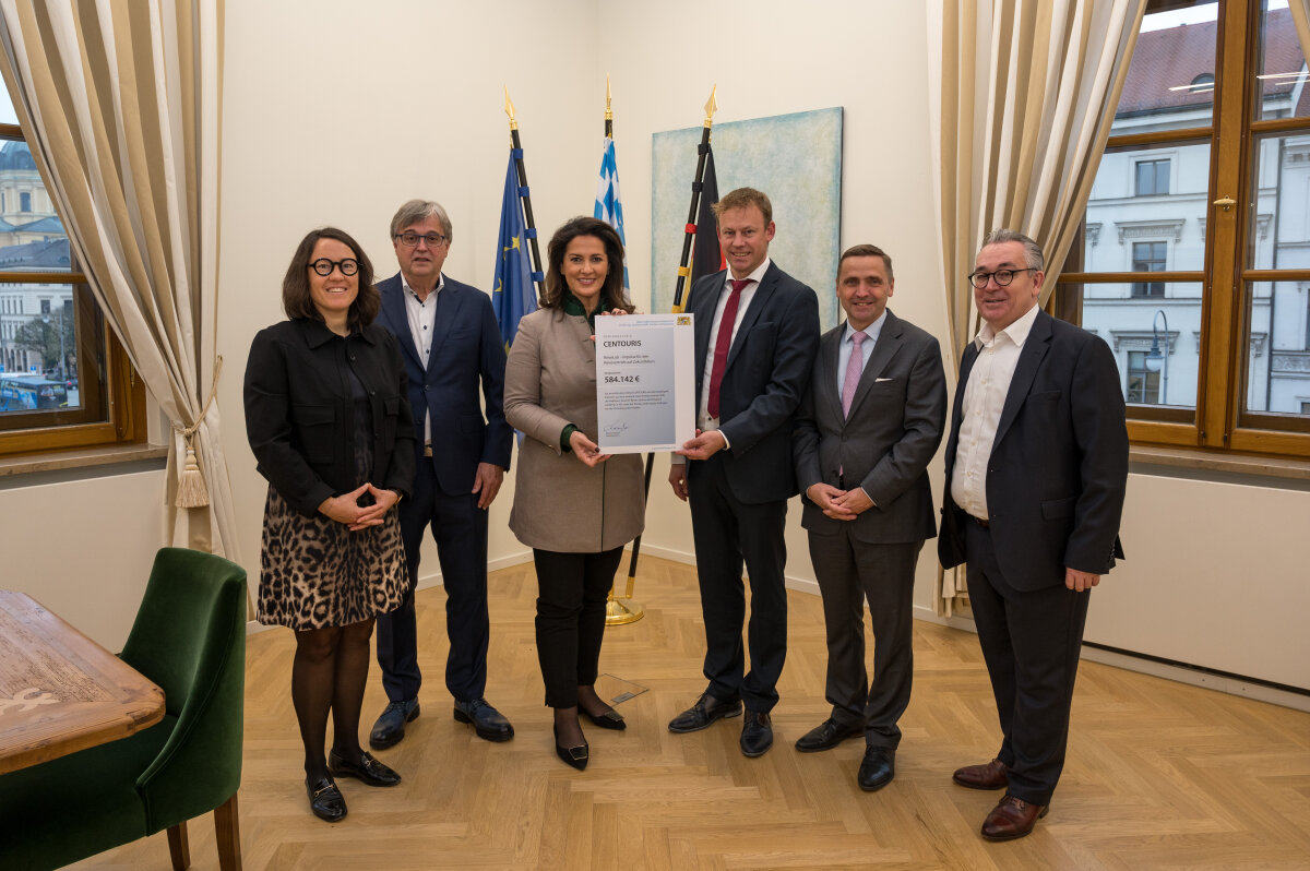 Dr. Janine Maier (Projektleiterin CENTOURIS, Universität Passau), Harald Reischel (Geschäftsführer Kermax GmbH), Tourismusministerin Michaela Kaniber, Dr. Stefan Mang (Geschäftsführer CENTOURIS - Universität Passau), Thomas Bösl (Direktor Strategy & International Relation - Raiffeisen Touristik Group Holding RTG) sowie Michael Buller (Vorstand VIR – Verband Internet Reisevertrieb) bei der Übergabe des Förderbescheids in München