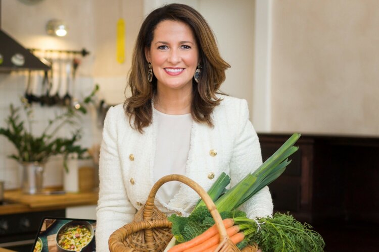 	 Landwirtschaftsministerin Michaela Kaniber steht hinter einem Korb mit Karotten und Lauch. Auf dem Tisch davor liegt weiteres Gemüse.