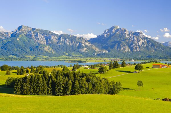 Landschaftsansicht mit Bergen und einem See im Hintergrund und Grasfläche im Vordergrund